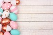 Easter egg side border. Rose gold, pink, turquoise and white colors on a white wood background.