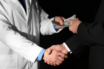 Poster - Doctor receiving bribe from businessman on black background, closeup