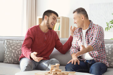 Canvas Print - Mature man playing board game with his son at home