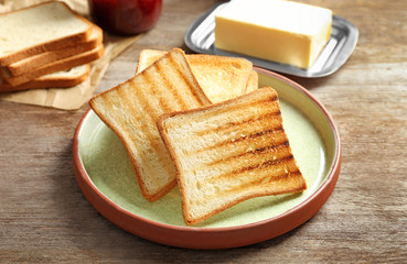 Sticker - Plate with tasty toasted bread on wooden table