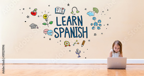 Learn Spanish text with little girl using a laptop computer on floor Canvas Print