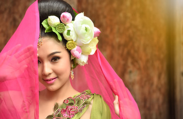 Asian fairy goddess adorned with lotus flowers, she was smiling beautifully on a wooden background with evening light.