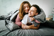 Cheerful couple under the coverlet in their bed. Artwork. Soft focus