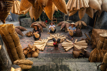 Old Vietnamese female craftsman making the traditional bamboo fish trap or weave at the old traditional house in Thu sy trade village, Hung Yen, Vietnam, traditional artist concept