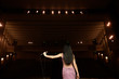 © nagaets - Beautiful singer against the auditorium. Back view girl in long gown performing on stage.