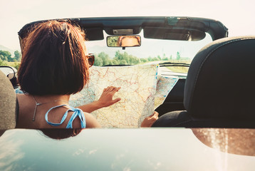 Wall Mural - Woman reads roads map sitting in cabriolet car