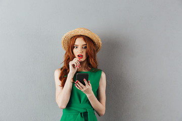 Wall Mural - Redhead young shocked confused woman chatting by phone.