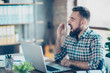 © deagreez - Concept of working day and night without having a recreation. Half-turned photo of exhausted powerless yawning tired young wearing casual checkered shirt office worker sitting in front of netbook