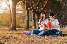 Man And Woman Sitting And Reading A Book In Park
