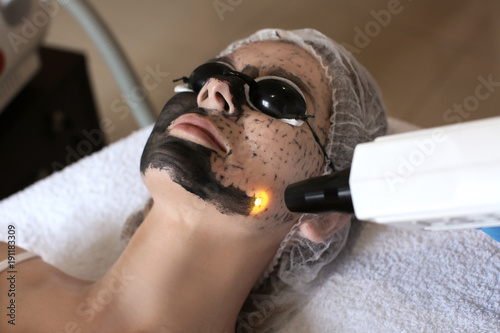 Fotomural Young woman undergoing carbon peeling procedure in salon