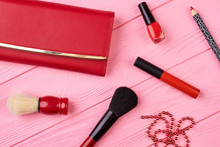 Makeup Cosmetics And Red Purse. Set Of Decorative Colorful Cosmetics Products And Facial On Pink Wood Table Background. Fashion Lady Stylish Essentials.