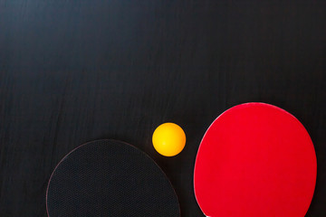 Two table tennis or ping pong rackets and ball on a black background