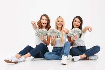 Wall Mural - Cute pretty girls friends showing money pointing.