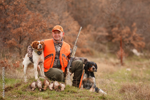 Fotografia, Obraz hunter with two hunting dogs, a gun and a woodcock after a hunt