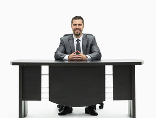 confident businessman sitting behind a Desk. isolated on white.