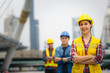 © smilepoker - Portrait of young engineer girl, posing outdoor with team and construction on background