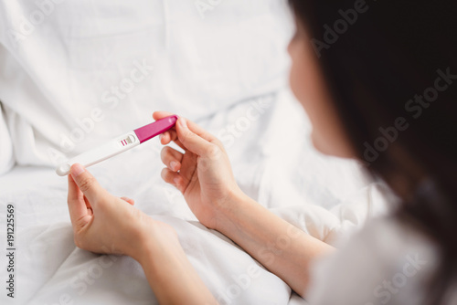 Fotografía back view of happy smile woman looking at pregnancy test with positive result in