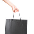 Female hand carry black paper shopping bag with white background. Isolated