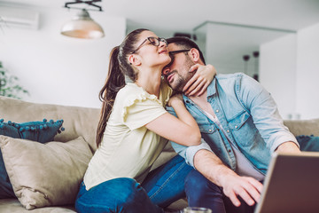 Happy couple with laptop spending time together at home