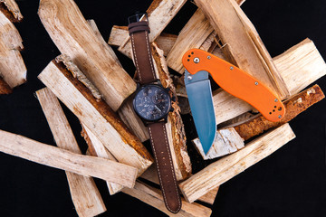 watch mens on wood. Black dial. Knife with orange handle