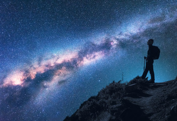 Wall Mural - space with milky way. silhouette of a woman with backpack at night. girl on the mountain peak and st