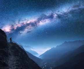 Wall Mural - space with milky way, girl and mountains. silhouette of standing woman on the mountain peak, mountai