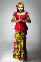 Wall Mural - Black female showing african pride by wearing a traditional Nigerian dress and head scarf with tribal face markings or cosmetic makeup.  The costume is red and yellow and shows cultural fashion.