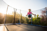 Fototapeta  - Fearless little kid jumping high on trampoline