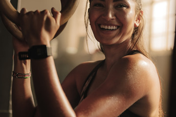 Wall Mural - Smiling woman exercising with gymnastic rings