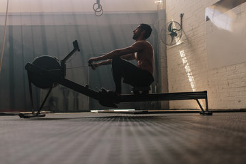 Wall Mural - Fit man doing cardio workout in gym