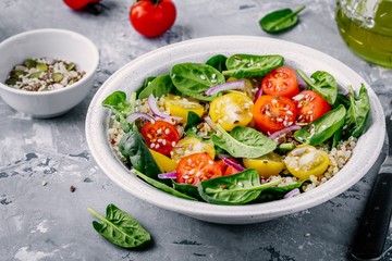 Wall Mural - Healthy green bowl salad with spinach, quinoa, yellow and red tomatoes, onions and seeds