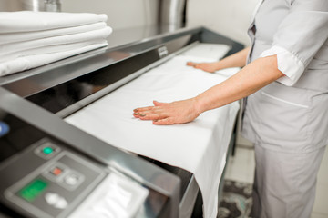 Ironing bedclothes with professional ironing machine in the laundry