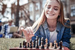 © Viacheslav Yakobchuk - Interesting game. Happy positive young woman looking at the chess board and smiling while enjoying the game
