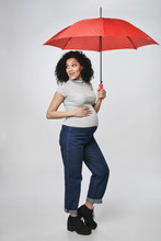 Pregnant Woman Standing In Full Length Under Red Umbrella Smiling Looking Back Over Shoulder At Empty Copy Space, Over White Background