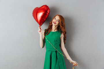 Poster - Smiling redhead young holding heart balloon.