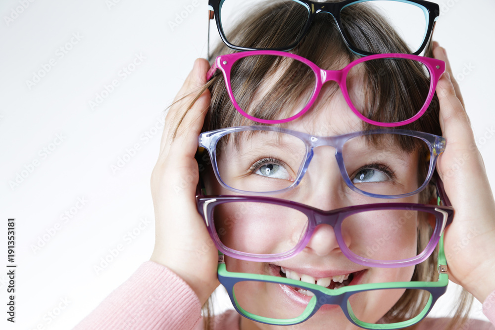 Dziewczynka trzyma kolorowe oprawki okularów.  - obrazy, fototapety, plakaty 