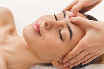 Woman getting professional facial massage at beauty salon