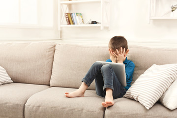 Crying boy with digital tablet at home