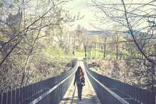 Lonely Girl Crosses A Bridge, On The Top Of Picture There Is Brunico's Castle In Trentino Alto Adige, Italy
