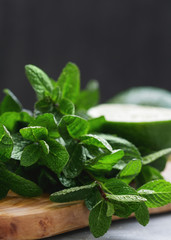 Wall Mural - Close-up of fresh mint and lime on a wooden cutting board on a table. Food background. Copy space.