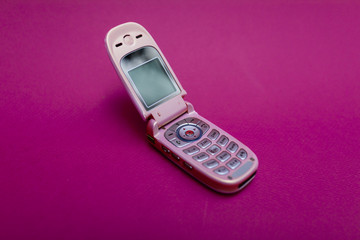 cool and classic pink retro flip cell or mobile phone isolated against a red background