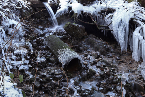 Fotografie, Obraz Langzeitbelichtung von einem Bach mit vielen Eiszapfen