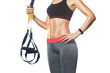 A slender girl holds a strap in her hand for the suspension training in the gym. Sports concept and healthy lifestyle.