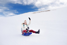 Happy Middle Age Woman Having Fun During Rolling Down The Mountain Slope On Sled In Alps