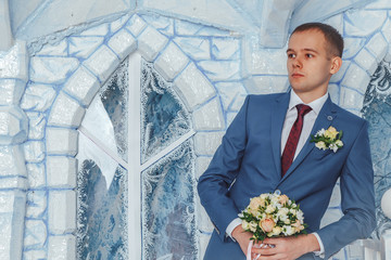 Portrait handsome groom in a blue suit wait bride in the Studio