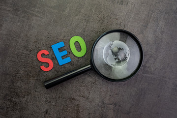 Aufkleber - globe on magnifier glass, alphabet word seo in red, blue and green on dark cement chalkboard backgro