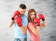 Angry couple in boxing gloves on grey background