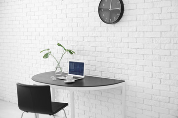 Poster - Comfortable home workplace with laptop on desk against brick wall