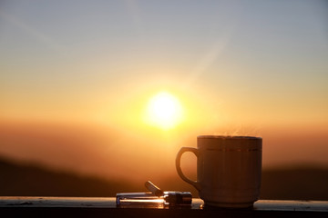 Morning cup of coffee and cigarette with mountain background at sunrise, Silhouettes on sunrise morning coffee , soft and select focus..