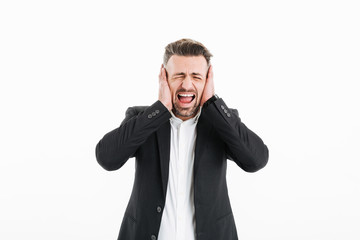 Canvas Print - Photo of businessman in suit with closed eyes screaming and covering his ears with both hands, isolated over white background